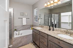 Bathroom featuring shower with separate bathtub and double sink vanity