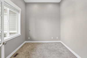 Room featuring neutral-toned walls, white baseboards, and plush gray carpeting