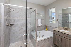 Bathroom featuring vanity with extensive cabinet space and separate shower and tub