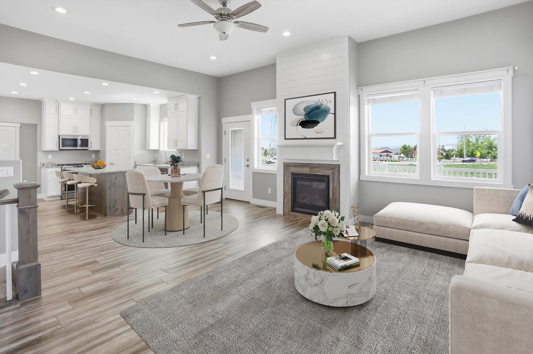 Open-concept living area with light-toned wood-finish flooring, a contemporary fireplace with wood-tile surround and shiplap accent, and a kitchen featuring white cabinetry and stainless steel appliances