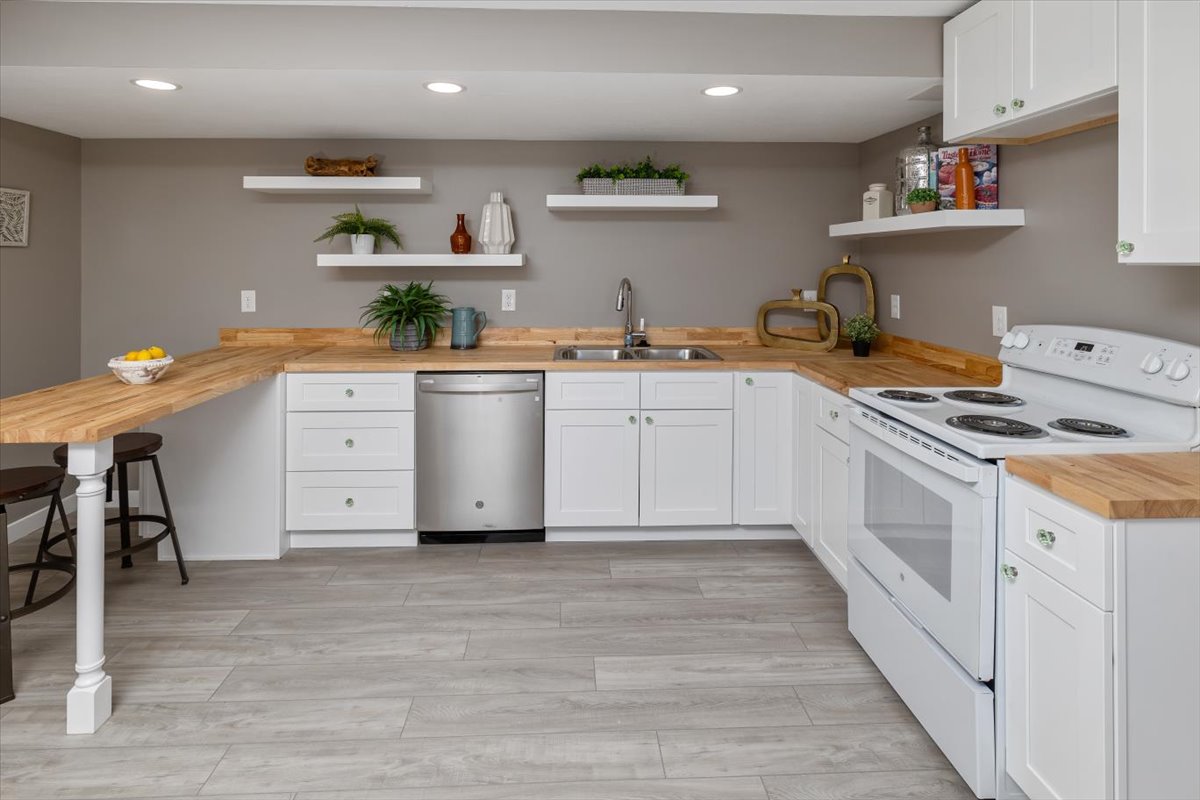Kitchen featuring white range with electric stovetop, white cabinetry, stainless steel dishwasher, wooden counters, and sink