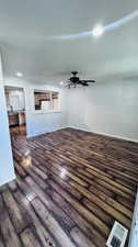 Unfurnished living room featuring a textured ceiling, dark wood-type flooring, and ceiling fan