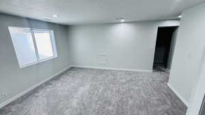 Carpeted spare room featuring a textured ceiling