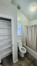 Bathroom featuring tile floors, vaulted ceiling, toilet, and shower / tub combo