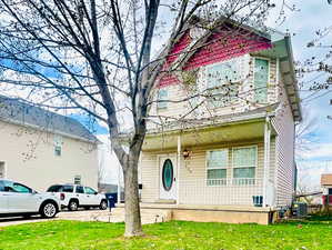 Exterior space with a front lawn, central air condition unit, and covered porch