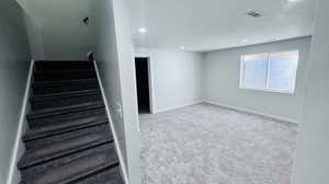 Staircase with a textured ceiling and carpet flooring