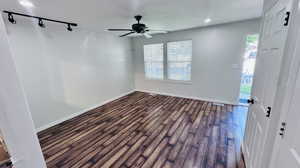 Empty room with track lighting, a textured ceiling, ceiling fan, and dark hardwood / wood-style floors