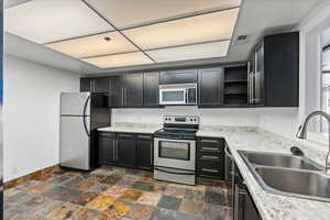 Kitchen featuring dark tile flooring, stainless steel appliances, and sink