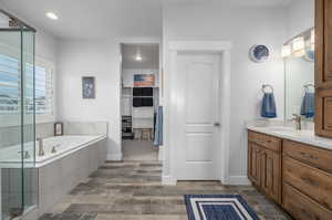 Bathroom featuring a relaxing tiled bath, wood-type flooring, and large vanity