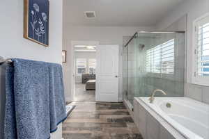 Bathroom with ceiling fan, hardwood / wood-style flooring, and separate shower and tub