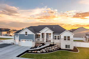 View of front of property featuring covered porch, a garage, and a yard