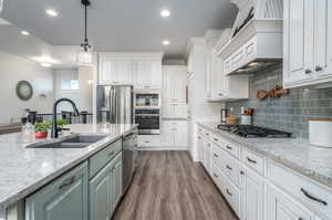 Kitchen with white cabinetry, dark hardwood / wood-style flooring, appliances with stainless steel finishes, backsplash, and pendant lighting