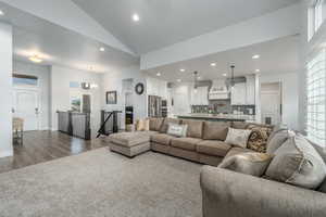 Living room with a notable chandelier, wood-type flooring, plenty of natural light, and lofted ceiling