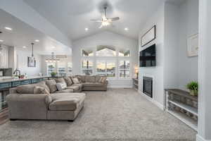 Living room with ceiling fan, vaulted ceiling, and light colored carpet