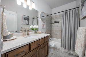 Full bathroom with tile flooring, shower / bath combination with curtain, toilet, and vanity with extensive cabinet space