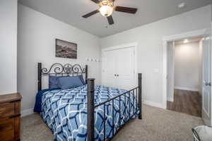 Carpeted bedroom with ceiling fan and a closet