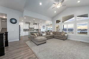 Living room with high vaulted ceiling, wood-type flooring, and ceiling fan