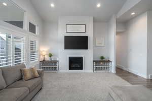 Carpeted living room featuring high vaulted ceiling and a healthy amount of sunlight