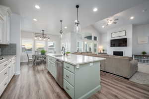 Kitchen with a center island with sink, stainless steel dishwasher, wood-type flooring, tasteful backsplash, and ceiling fan