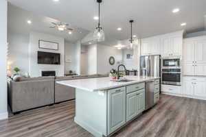 Kitchen with stainless steel appliances, wood-type flooring, sink, and a kitchen island with sink