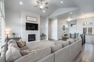 Living room with high vaulted ceiling, wood-type flooring, and ceiling fan with notable chandelier