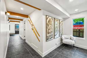 Hallway with beamed ceiling and dark tile floors