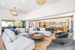 Living room featuring a towering ceiling, a chandelier, and light hardwood / wood-style flooring