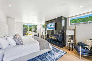 Bedroom with a large fireplace and light hardwood / wood-style flooring