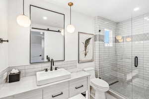 Bathroom featuring a shower with shower door, backsplash, vanity, and toilet