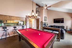 Playroom with a stone fireplace, carpet floors, beamed ceiling, ceiling fan with notable chandelier, and pool table