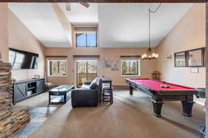 Rec room with carpet flooring, a notable chandelier, billiards, high vaulted ceiling, and a baseboard radiator