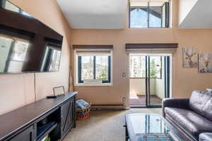 Living room with a baseboard heating unit and light carpet