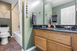 Full bathroom featuring tile floors, shower / tub combo, large vanity, and toilet