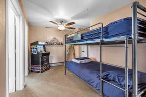 Carpeted bedroom featuring a baseboard heating unit and ceiling fan