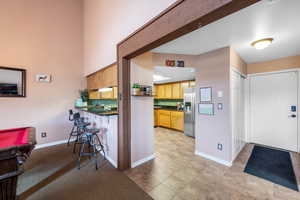 Kitchen with billiards, stainless steel fridge, and light tile flooring