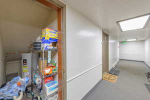 Interior space with a textured ceiling, water heater, and carpet floors