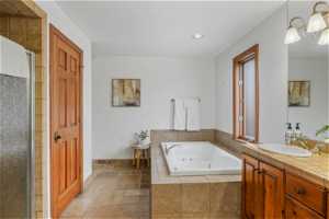 Bathroom with tile flooring, shower with separate bathtub, and vanity with extensive cabinet space