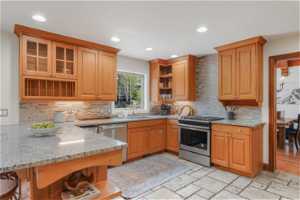 Kitchen featuring stainless steel appliances, light stone counters, sink, tasteful backsplash, and light tile floors
