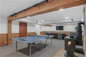 Rec room with beam ceiling, carpet flooring, and a wood stove