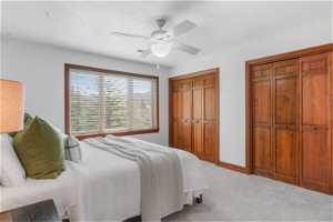 Carpeted bedroom with two closets and ceiling fan