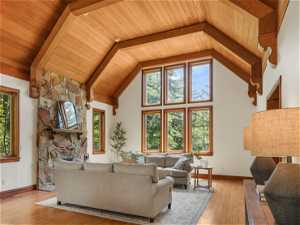 Living room featuring a wealth of natural light, wood-type flooring, high vaulted ceiling, and wood ceiling