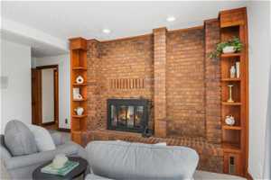 Living room with brick wall, a textured ceiling, and a fireplace