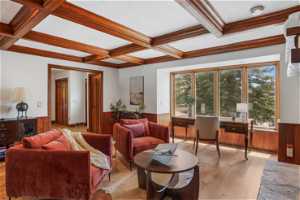 Living room with wood-type flooring, coffered ceiling, beam ceiling, and ornamental molding
