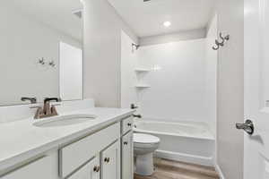 Full bathroom with toilet, vanity, tiled shower / bath, and hardwood / wood-style floors