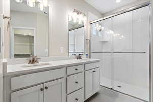 Bathroom featuring dual vanity, an enclosed shower, tile flooring, and a chandelier