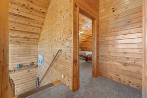 Interior space with wooden ceiling, wooden walls, lofted ceiling, and carpet floors