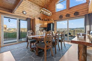 Dining area with a towering ceiling, a healthy amount of sunlight, hardwood / wood-style flooring, and rustic walls