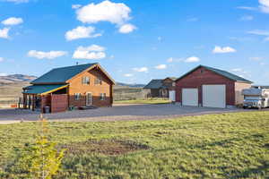 View of front of home with a front yard, a garage, a mountain view, and an outdoor structure