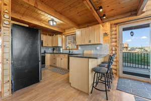 Kitchen with light wood-type flooring, beamed ceiling, log walls, backsplash, and wood ceiling