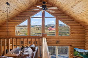 Interior space with a mountain view, wooden ceiling, high vaulted ceiling, rustic walls, and ceiling fan